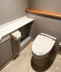 落ち着いたグレートーンで統一された清潔感のあるトイレ空間。手すり付きで使い勝手も良く、収納スペースも確保されており、日々の生活を快適にサポートします。