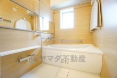 横長の鏡が、空間に奥行をもたらし、広々としたバスルームを印象付けています。浴室上部には洗濯物を掛けられる物干し竿が設置されています。