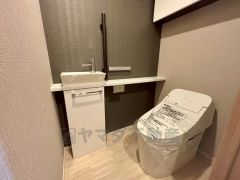 手洗い場を設けたトイレはスッキリとしたタンクレスを採用いたしました。 トイレ上部には扉付きの収納棚を設置済み。