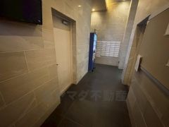 落ち着いたタイル仕上げが上質な雰囲気を演出するマンションロビー。自動販売機も設置された便利な共用スペースです。