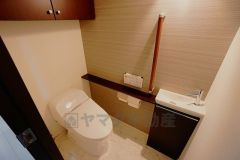 壁リモコンタイプのウォシュレット付き。すっきりした見た目で、トイレ奥の掃除もしやすいです。また棚やタオル掛け、手洗いも設けています。