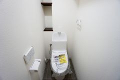壁リモコンタイプのウォシュレット付き。すっきりした見た目で、トイレ奥の掃除もしやすいです。トイレットペーパーの収納に便利な棚付き。